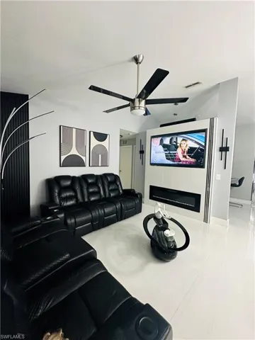 Home theater featuring ceiling fan, a fireplace, and visible vents