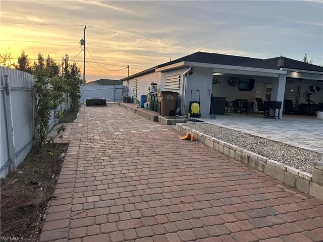 Property exterior at dusk with a fenced backyard, a patio, and stucco siding
