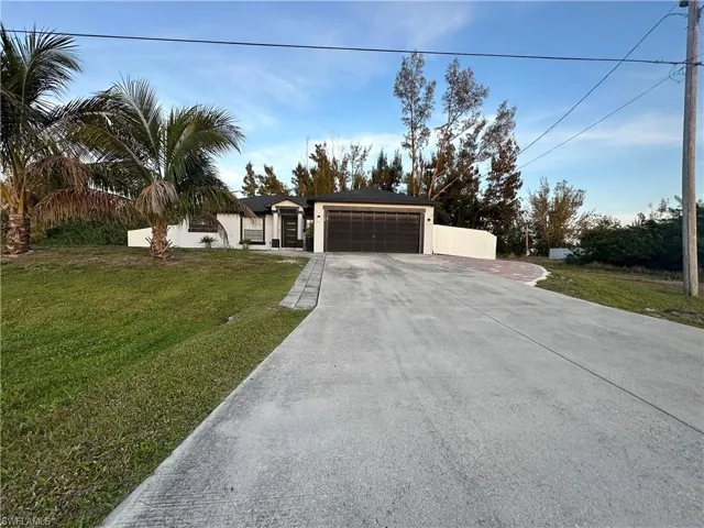 View of front of house with driveway, a front lawn, and an attached garage