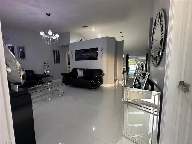 Living room with lofted ceiling, an inviting chandelier, and visible vents