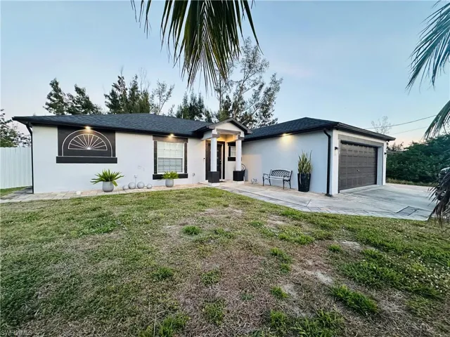 View of front of property with a front lawn, driveway, an attached garage, and stucco siding