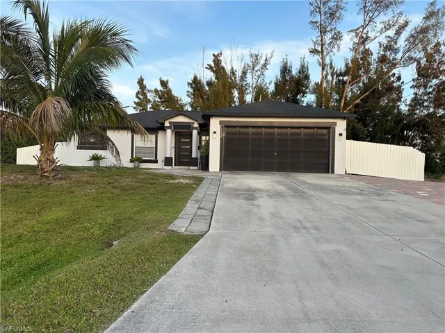 View of front of property with stucco siding, an attached garage, a front yard, fence, and driveway