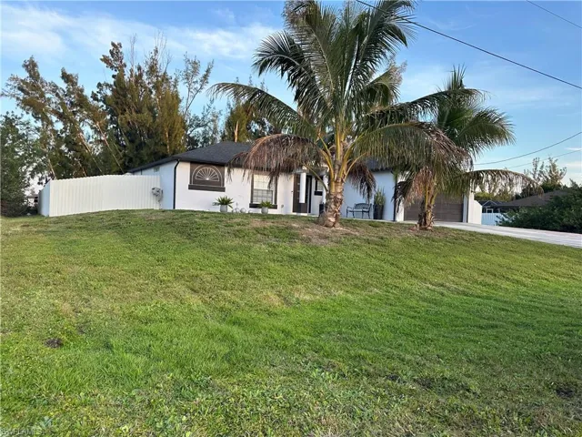 View of front of property with an attached garage, driveway, fence, and a front lawn