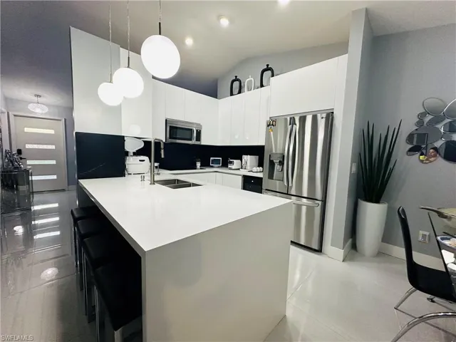 Kitchen featuring a breakfast bar area, stainless steel appliances, light countertops, and pendant lighting