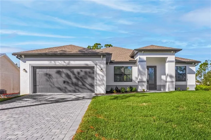 Prairie-style home with a front lawn, driveway, stucco siding, a garage, and a shingled roof