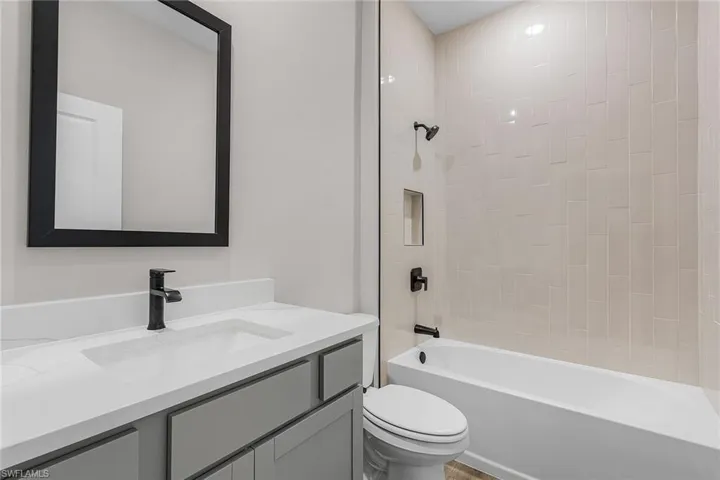 Kitchen featuring stainless steel appliances, gray cabinets, tasteful backsplash, wood tiled floors, and a center island with sink