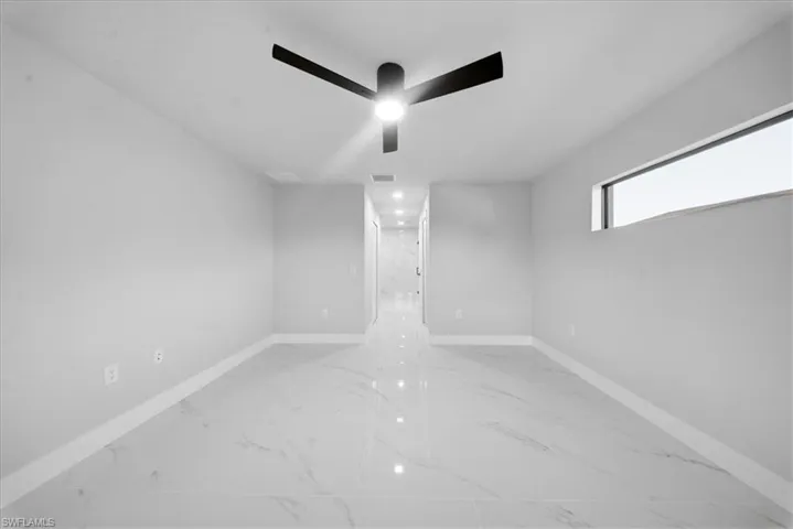 Spare room with light marble finish floors and a ceiling fan