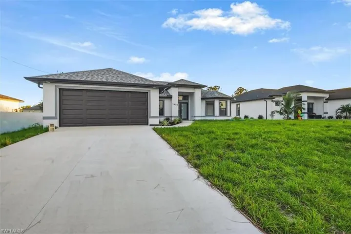 Prairie-style house with stucco siding, driveway, a front lawn, a garage, and a shingled roof