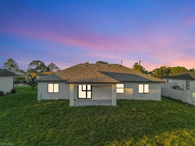 Back of house featuring stucco siding, a patio, and roof with shingles