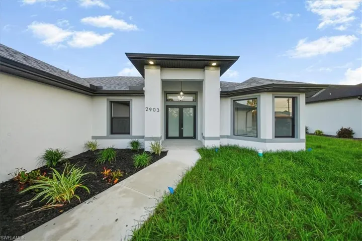 Property entrance with stucco siding, french doors, and a yard