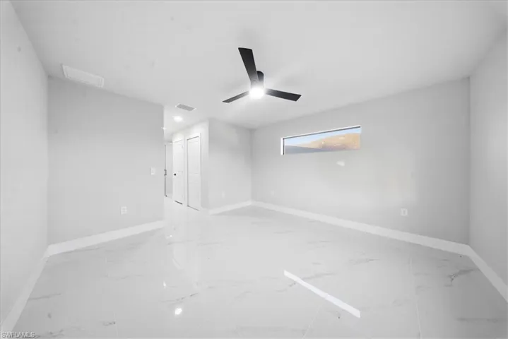 Unfurnished room with light marble finish floors and a ceiling fan
