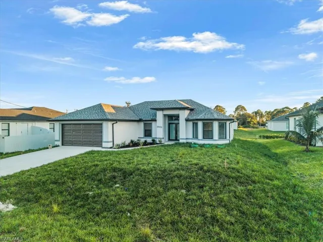 View of front of home with driveway, a front lawn, a garage, and stucco siding