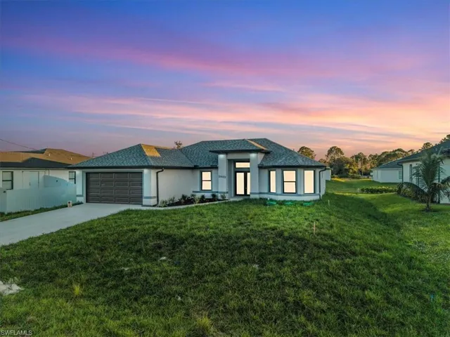 View of front of home with driveway, a front lawn, an attached garage, and stucco siding