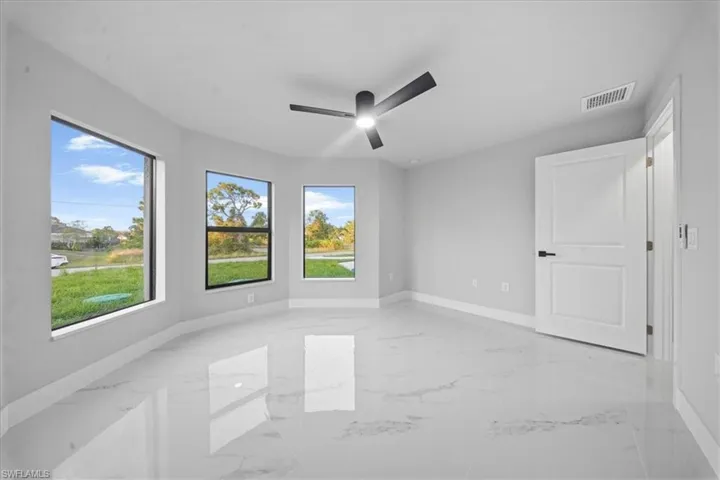 Empty room featuring light marble finish floors and ceiling fan