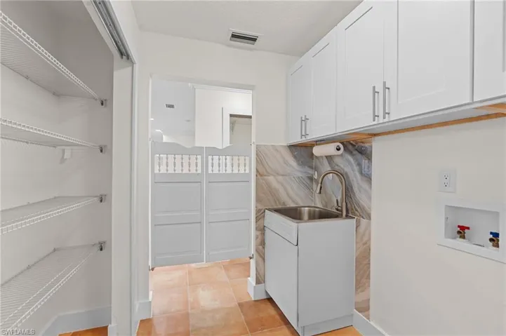 Clothes washing area featuring cabinets, light tile patterned floors, sink, and hookup for a washing machine