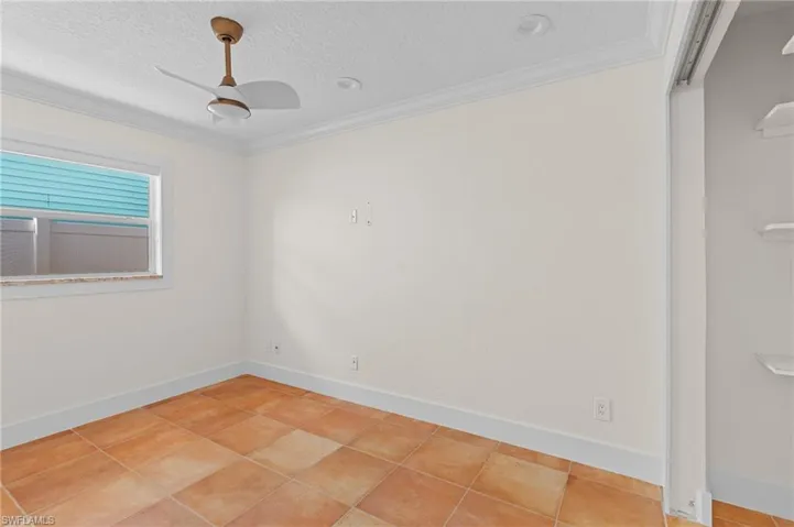 Unfurnished room with tile patterned floors, ceiling fan, ornamental molding, and a textured ceiling