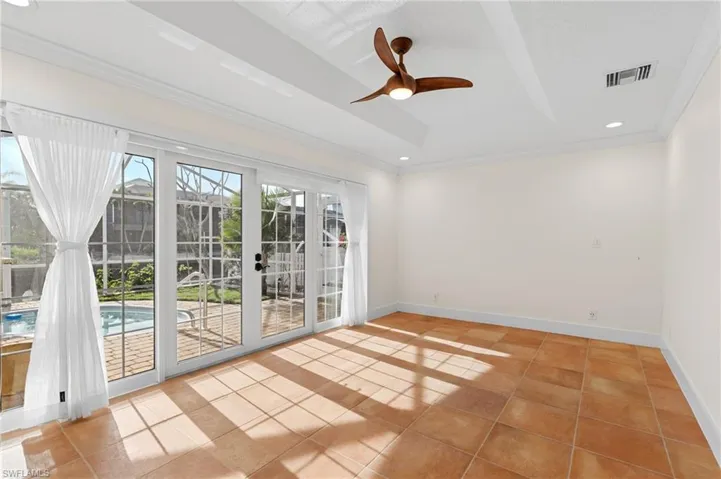 Empty room featuring ceiling fan, french doors, a raised ceiling, crown molding, and light tile patterned floors