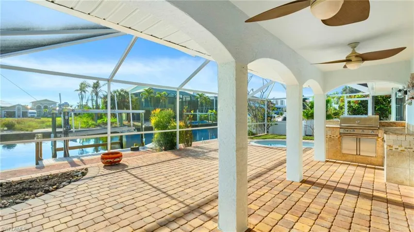 View of patio featuring glass enclosure, a grill, a water view, and area for grilling