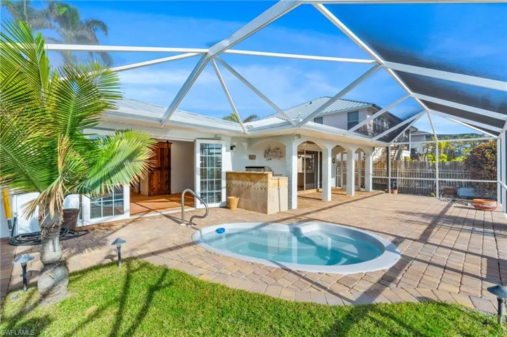 View of pool featuring a jacuzzi, a lanai, an outdoor bar, and a patio