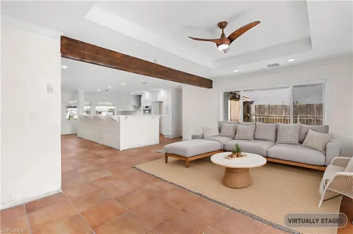 Tiled living room featuring a tray ceiling, ceiling fan, and crown molding