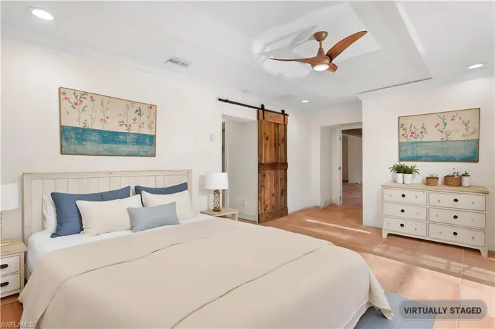 Bedroom featuring light tile patterned floors, a barn door, ceiling fan, and ornamental molding