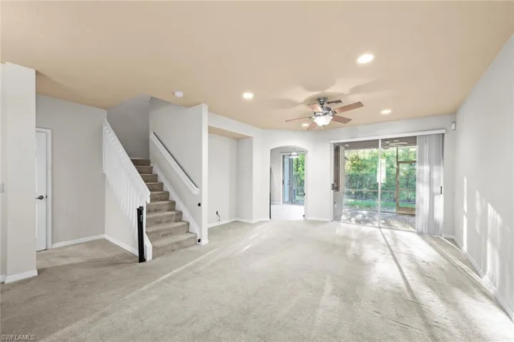 Unfurnished living room featuring ceiling fan and light colored carpet