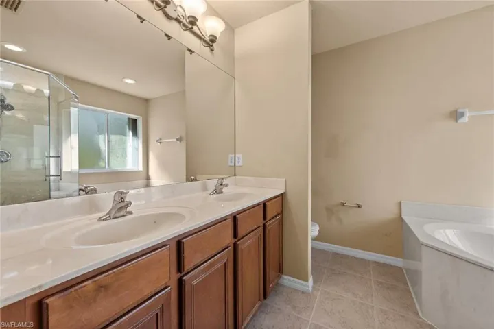 Full bathroom with plus walk in shower, vanity, tile patterned floors, and toilet