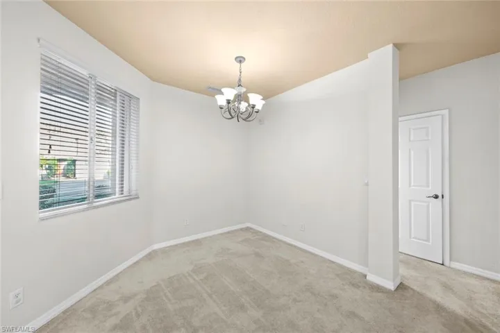 Unfurnished room featuring light colored carpet and a chandelier