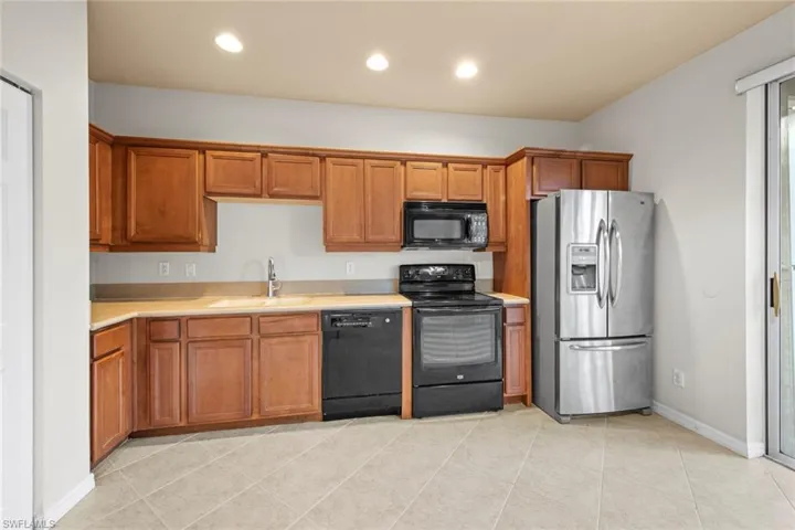 Kitchen with sink, light tile patterned floors, and black appliances
