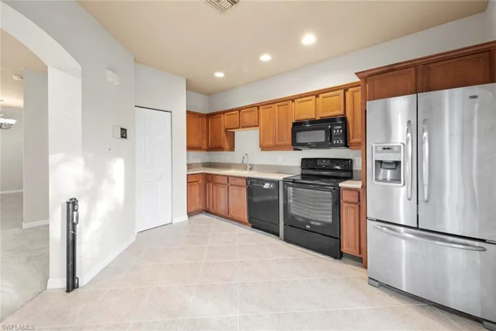 Kitchen with sink, light tile patterned floors, black appliances, and a chandelier
