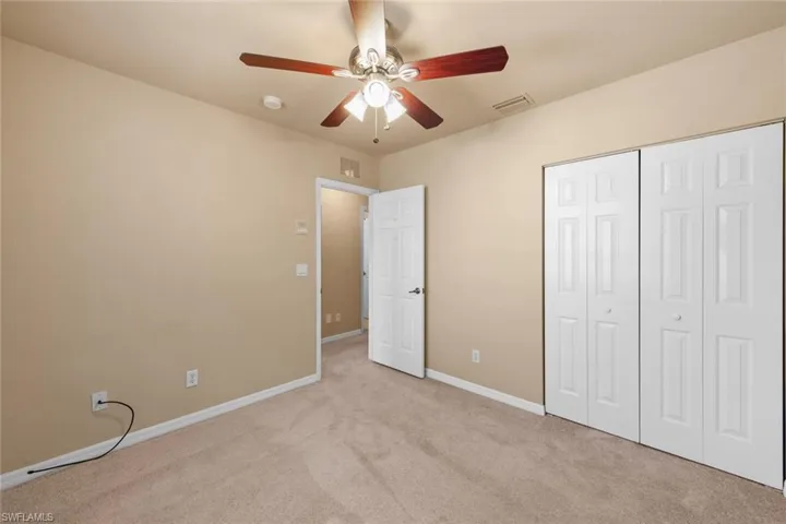 Unfurnished bedroom with ceiling fan, a closet, and light colored carpet