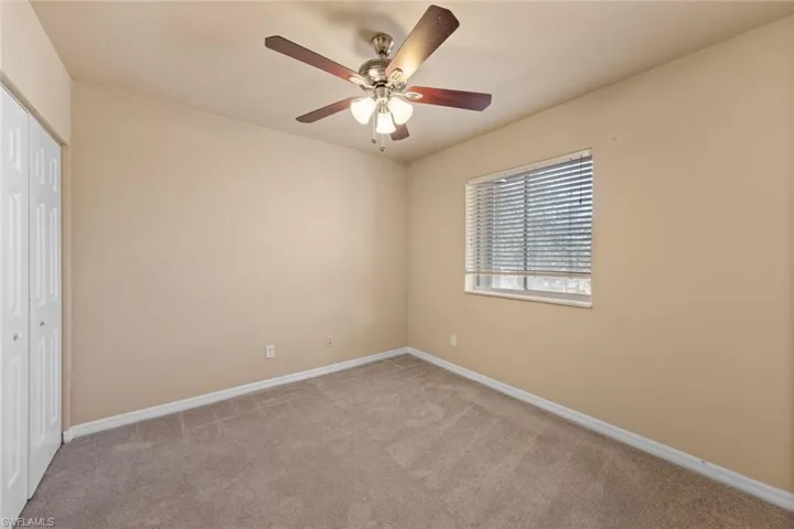 Unfurnished bedroom featuring ceiling fan, a closet, and light carpet