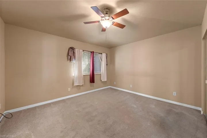 Carpeted spare room featuring ceiling fan