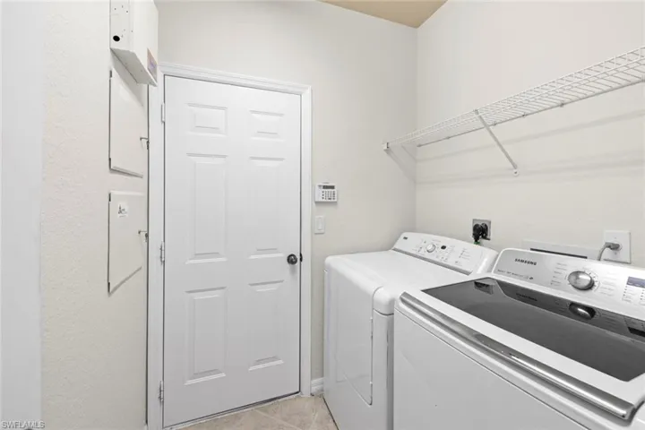Washroom with light tile patterned floors and washer and clothes dryer