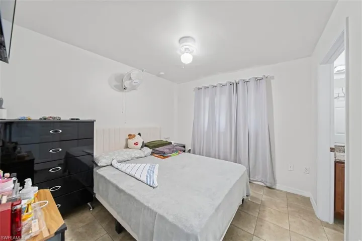 Room featuring tiled flooring, a window with curtains, and a ceiling-mounted light fixture