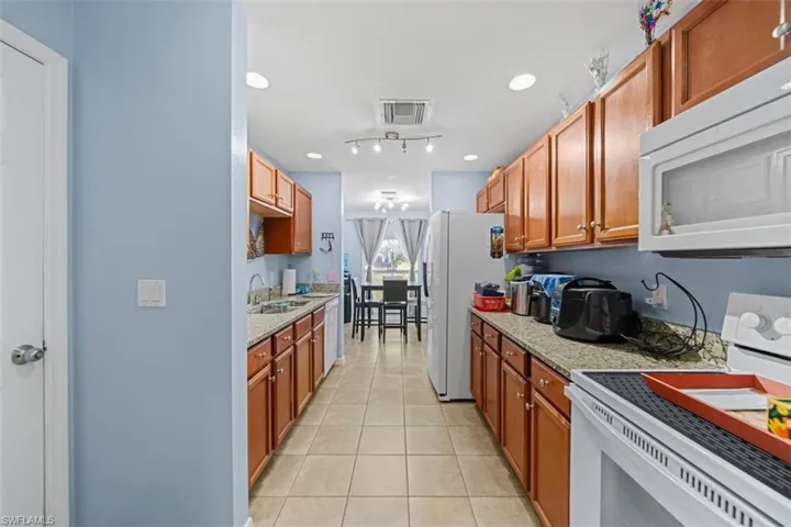 Galley kitchen featuring wood cabinetry, light-toned countertops, and tile flooring
