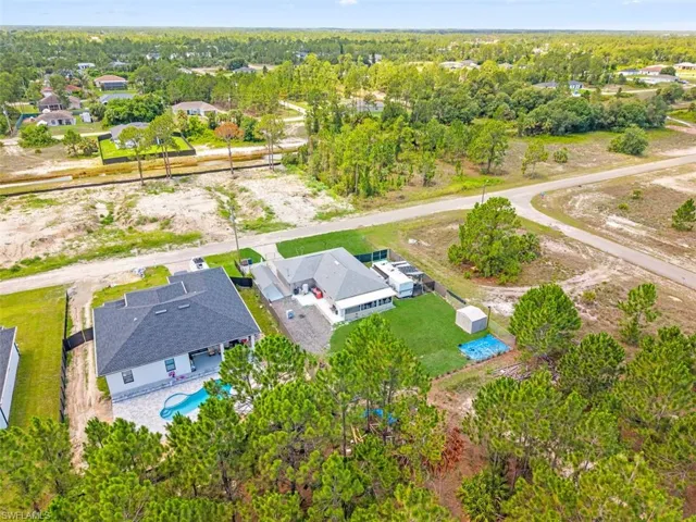 Aerial perspective showcasing a residential property with a dark shingle roof and a light-colored exterior