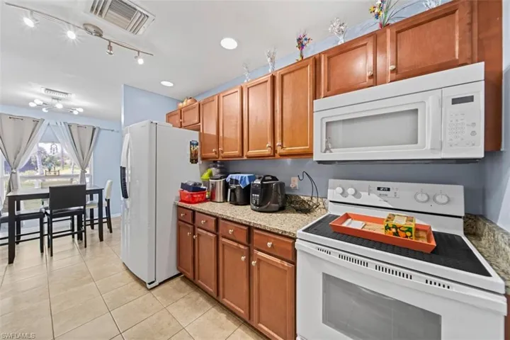 Kitchen featuring wood cabinetry, granite-look countertops, and tile flooring
