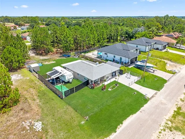 Fenced property featuring a large manicured lawn, an extended driveway, and a separate structure with covered parking