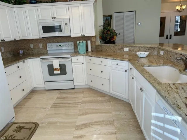 Kitchen with white cabinetry, sink, and range