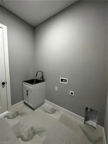 In house laundry room with custom cabinet sink and washer / dryer hookup