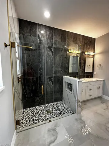 Custom shower with gold detailing and custom tiled floor and niche