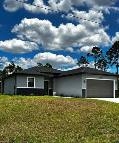 View of front of property featuring a garage and a front lawn