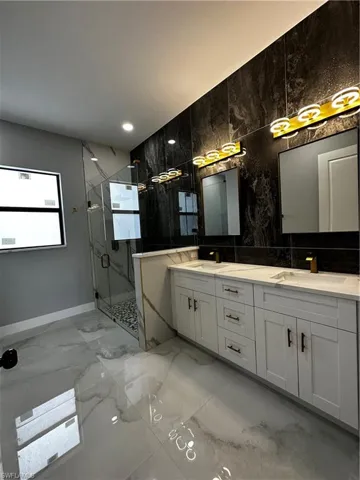 Master bathroom with custom tiled wall, glass shower and dual sinks