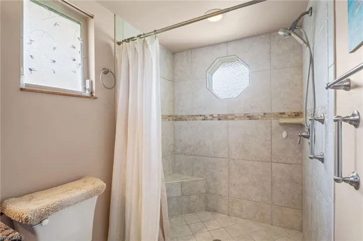 Full bath with tiled shower and toilet