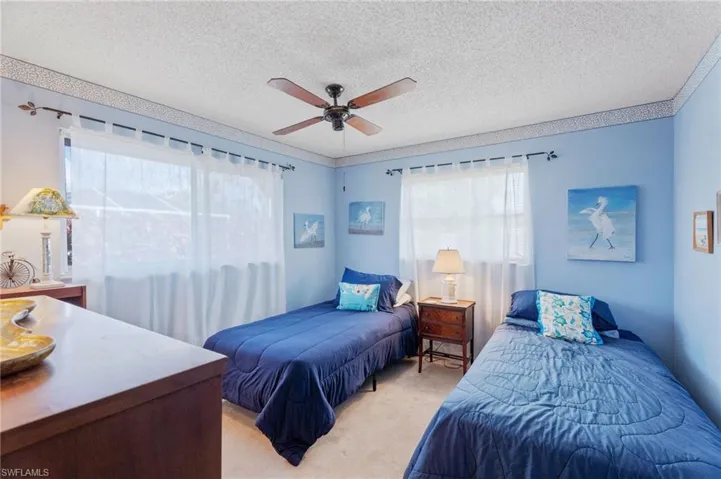 Bedroom featuring light carpet, a textured ceiling, and a ceiling fan