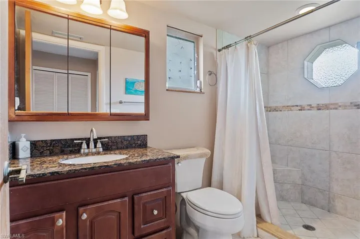 Full bath featuring vanity, toilet, and tiled shower