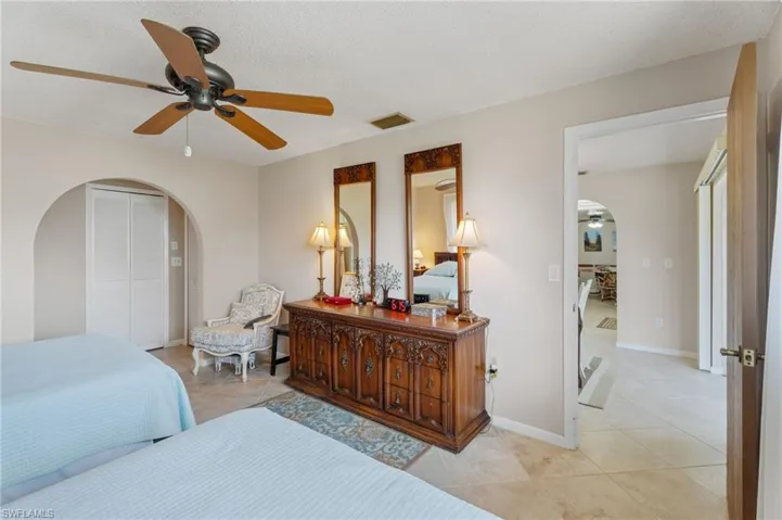 Bedroom with arched walkways, light tile patterned floors, a closet, and baseboards