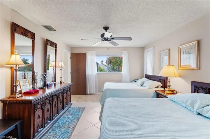 Bedroom with light tile patterned floors, a textured ceiling, and a ceiling fan