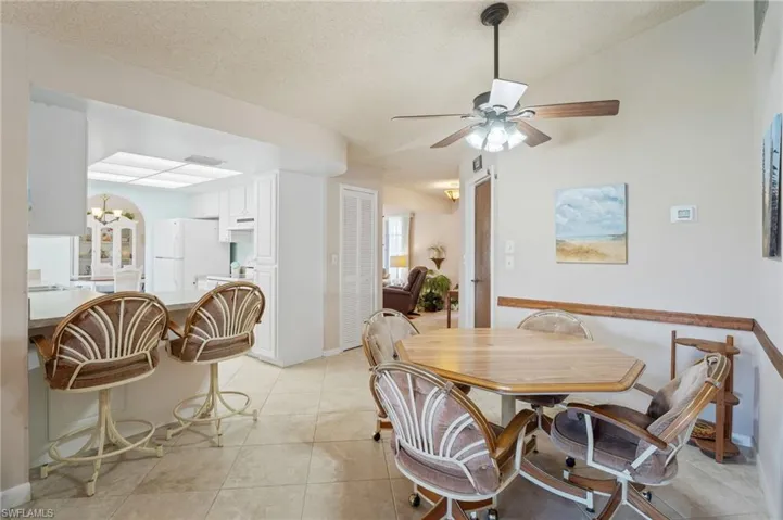 Dining room with a ceiling fan, light tile patterned flooring, a chandelier, a textured ceiling, and baseboards